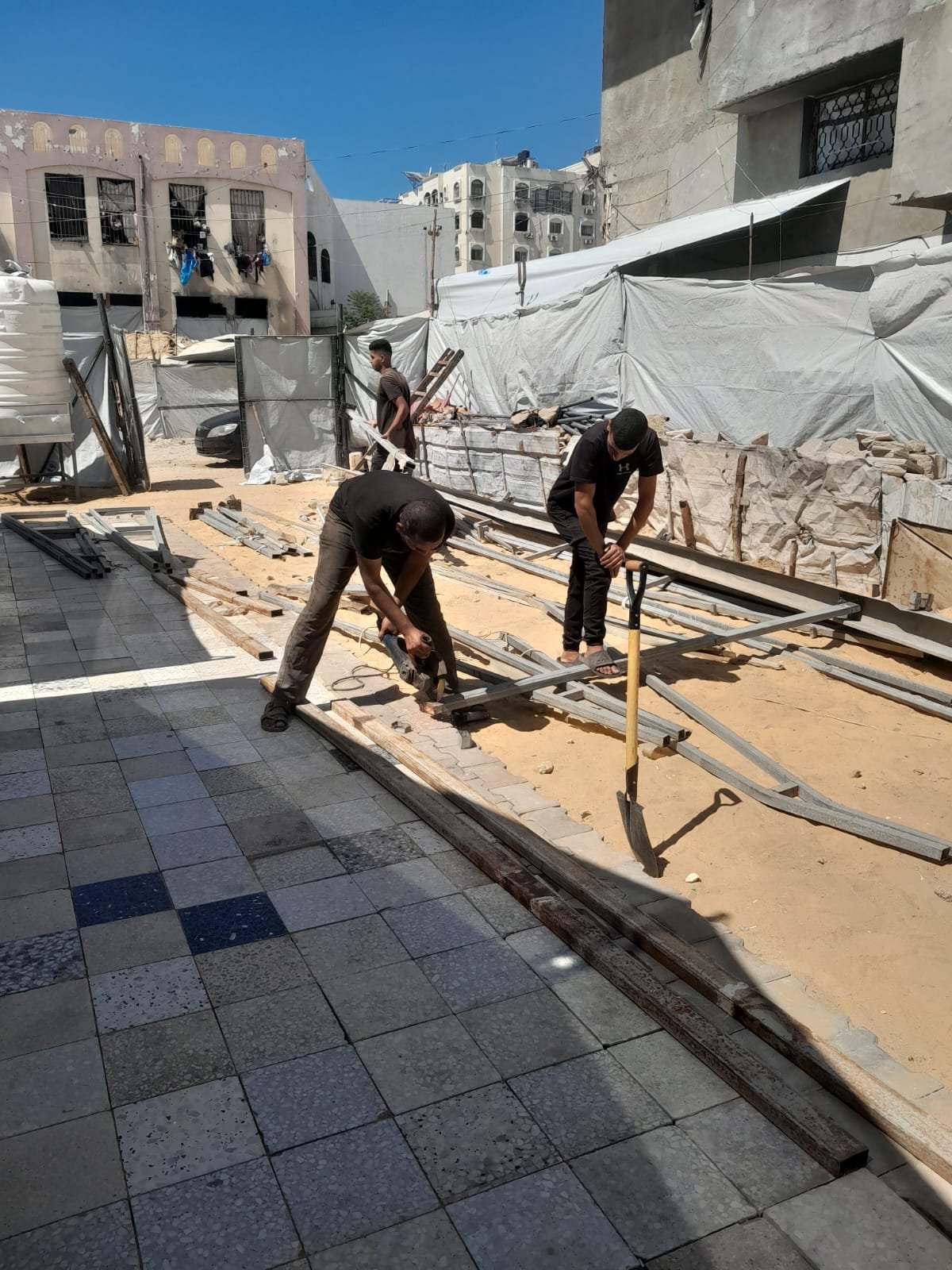 From the Ground Up: Building Al-Lababidi Clinic in Gaza Workers assembling metal members beside a tiled clinic pathway