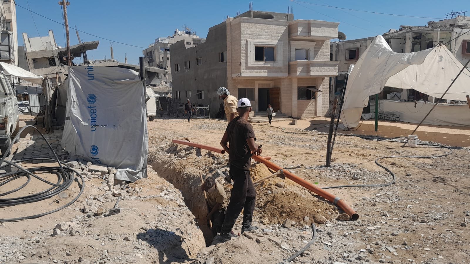 From the Ground Up: Building Al-Lababidi Clinic in Gaza Workers excavating a trench and laying pipes beside the clinic tents
